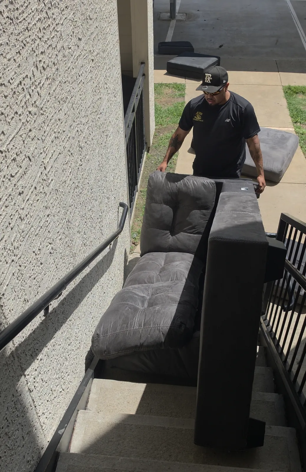 Crew carrying couch down apartment stairs