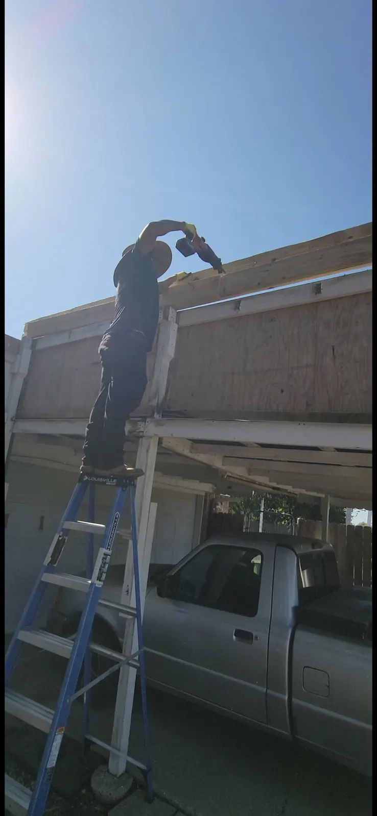 Crew member on ladder demolishing patio cover